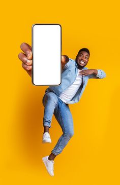 a man in jeans and white shirt holding up a cell phone with his right hand