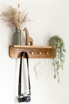 a wooden shelf holding two cameras and a camera strap hanging from it's side