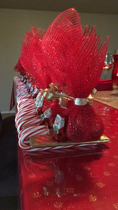 a red table topped with candy canes and a vase filled with flowers on top of it