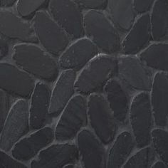 a black stone wall with some small rocks on it