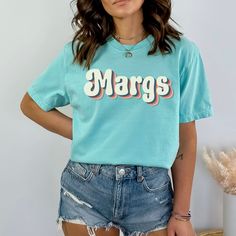 Do you know anyone who loves margaritas? Then this t-shirt is the perfect gift for her! This t-shirt features a fun design with the words “Margs”. It’s made from Comfort Colors® fabric, which is soft, cozy, and durable. It’s also available in different colors and sizes to suit her style and preference. This t-shirt is ideal for Cinco de Mayo, Cinco de Drinko, or any fiesta where she wants to enjoy a delicious drink. It’s also a cute margs shirt that she can wear anytime she feels like a margarita lover. Order yours today and surprise your mom, your bff with this trendy fiesta shirt or get one for yourself!Comfort Colors introduces its garment-dyed t-shirt; a fully customizable tee made 100% with ring-spun cotton. The soft-washed, garment-dyed fabric brings extra coziness to your wardrobe w Mamacita Needs A Margarita Shirt, Cinco De Mayo Screen Print Crew Neck T-shirt, Fun Crew Neck T-shirt For Cinco De Mayo, Cheap Casual T-shirt For Cinco De Mayo, Margarita Shirt, Cinco De Drinko, Cinco De Mayo Graphic Cotton T-shirt, Fiesta Shirt, Retro Floral