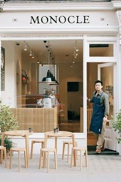 a man standing in front of a store with lots of chairs and tables around it