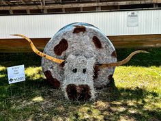 a fake cow is sitting in the grass with a sign on it's side