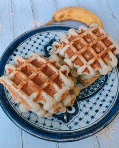 two waffles on a blue and white plate next to a banana