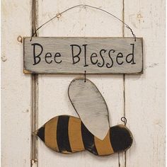 a wooden sign with a bee hanging from it's side on a white door