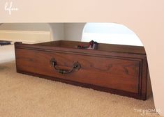 an empty wooden box sitting on the floor in front of a wall with a mirror above it