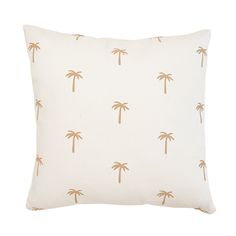 a white and gold pillow with palm trees on the front, against a white background