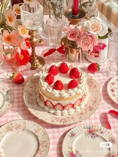 a table topped with plates and cake covered in strawberries