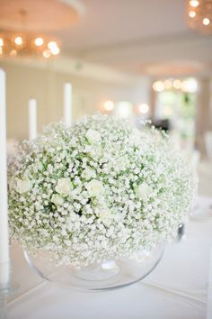 a vase filled with baby's breath sitting on top of a white table cloth