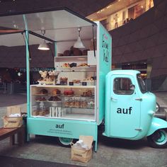 an ice cream truck parked in front of a building with food on display behind it