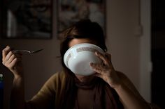 a woman holding a spoon and fork in front of her face