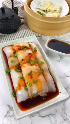 some food is sitting on a white plate with sauce and chopsticks next to it