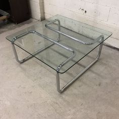 two glass tables sitting on top of each other in front of a white brick wall