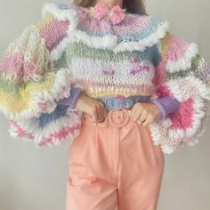 a woman wearing pink pants and a multicolored knitted sweater with puffy sleeves