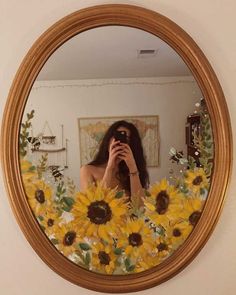 a woman taking a selfie in front of a mirror with sunflowers on it