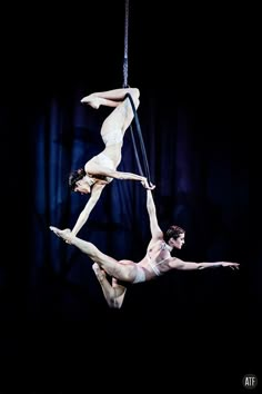 two acrobatic performers performing aerial acrobatic tricks on a rope