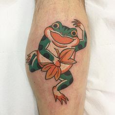 a frog with an orange and green bow on it's back leg is shown