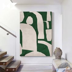 an abstract painting hangs on the wall next to some stairs and a vase with a rock in it