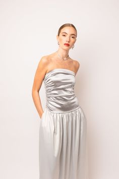 a woman in a silver dress posing for the camera with her hands on her hips