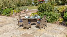 an outdoor dining table and chairs set up in the middle of a stone patio area