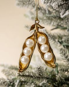 an ornament hanging from a christmas tree decorated with pearls and gold leaf shapes