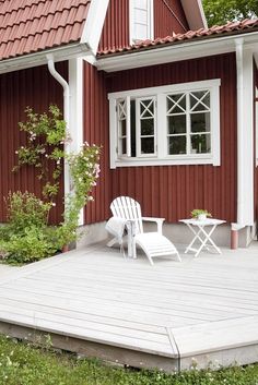 a white chair sitting on top of a wooden deck next to a red and white house