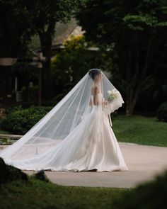 the bride is walking down the sidewalk with her veil blowing in the wind