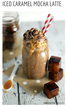 two jars filled with ice cream and caramel on top of a wooden table next to brown sugar cubes