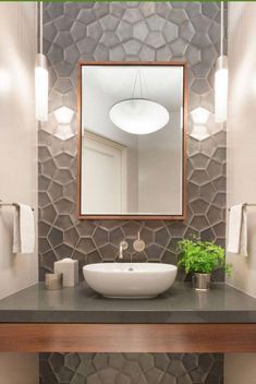 a bathroom with a sink, mirror and plants on the counter in front of it