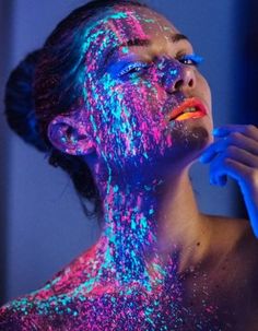 a woman is covered in colored powder and posing for the camera