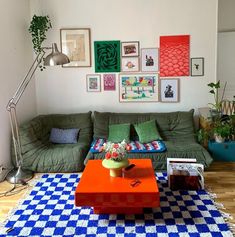 a living room with green couches and pictures on the wall above it's coffee table