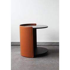 an orange table with a black base and a white wall in the backround