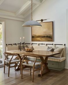 a dining room table with benches and candles on it in front of a painting hanging above