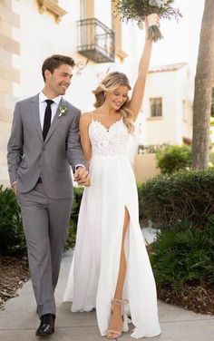 a man and woman walking down a sidewalk holding hands with each other, both dressed in grey suits