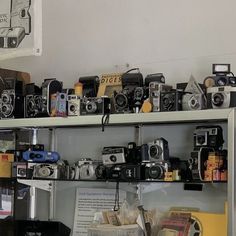 many different types of cameras sitting on shelves