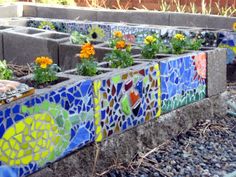 the garden is decorated with colorful tiles and flowers in it's planter boxes