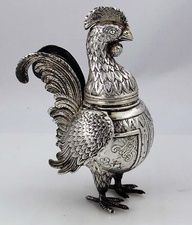 a silver rooster figurine sitting on top of a table