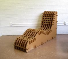 a cardboard sculpture made to look like a stair case in front of a white brick wall