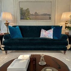 a living room with blue couches and two lamps on the tables in front of them