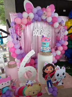 a birthday cake surrounded by balloons and other decorations on a table at a children's birthday party