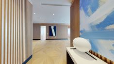 an abstract painting is on the wall in this modern hallway with white and blue accents