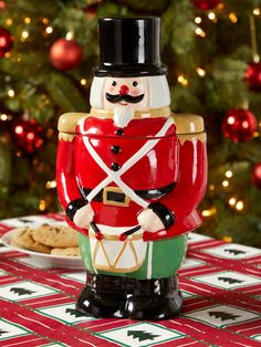 a nutcracker cookie jar sitting on top of a table next to a christmas tree