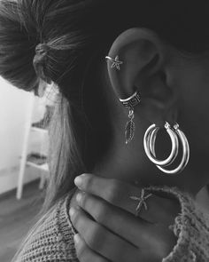 a woman wearing three pairs of hoop earrings