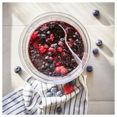 blueberries and raspberries in a blender with a spoon