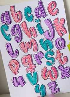 someone is holding up a poster with letters drawn on it and the letter's lowercases are in different colors