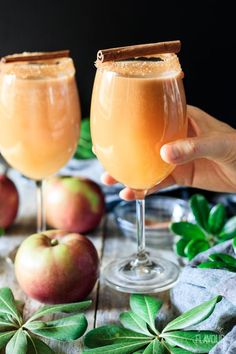 two glasses filled with apple cider sitting on top of a table