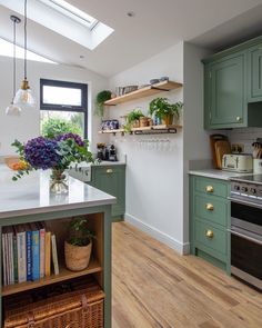 a kitchen with green cabinets and white counter tops next to a stove top oven under a skylight