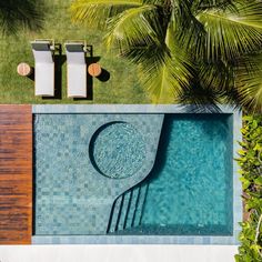 an aerial view of a swimming pool with lounge chairs and palm trees in the background