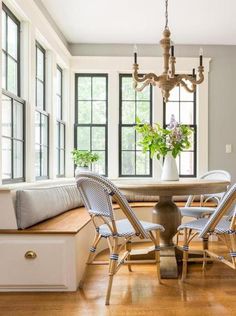 a dining room table with four chairs and a bench in front of the window seat