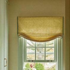 a window with a curtain over it and a vase filled with flowers on the windowsill